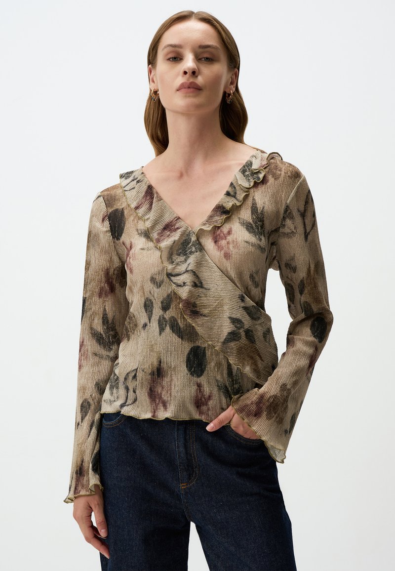 Bluse mit Blumenmuster in Beige- und Erdtönen, mit Rüschenausschnitt und langen Ärmeln, aus strukturiertem Stoff mit fransigen Kanten.