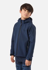 Boy wearing a navy blue hooded jacket and matching pants with zippered pockets, standing against a plain white background.