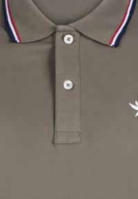 Polo de color verde aceituna con un tejido texturizado, que presenta un cuello contrastante en rayas de marino, rojo y blanco, y una tapeta con dos botones.