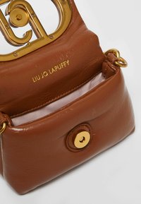 Brown leather handbag with a structured shape, gold hardware, and a logo. Inside lined with pink fabric and features a snap closure.