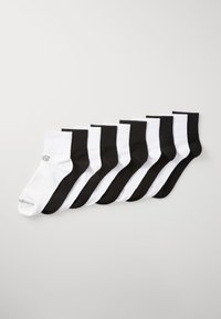 Eight pairs of ankle socks arranged in alternating black and white colors, featuring a small logo on one white sock.