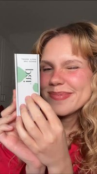 Witte rechthoekige doos met het label "Pestle" en groene ronde accenten. Bevat het huidverzorgingsproduct "gentle essentials", vastgehouden door een persoon met golvend haar.