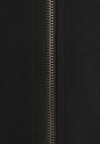 Black zip-up garment featuring a central metal zipper. The fabric appears smooth with a consistent texture.