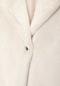 Witte nepbont jas met een zachte, pluche textuur, met een geklemd kraag en een enkele zwarte knoopdetails aan de voorkant.