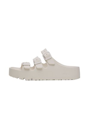 Sandali beige chiaro in gomma con tre fibbie regolabili e una suola testurizzata per una buona aderenza. Design sagomato con punta aperta.