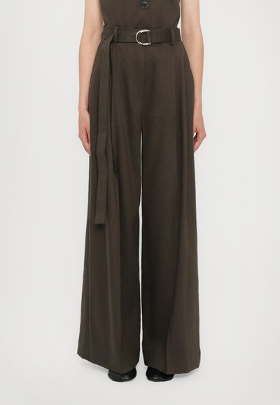 Pantaloni larghi marroni con vita cinturata, realizzati in un tessuto testurizzato. Presentano un grande bottone anteriore e una vestibilità morbida e rilassata.