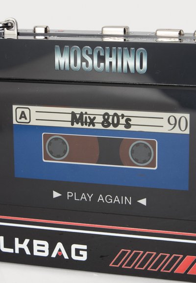 Sac Moschino noir conçu pour ressembler à une cassette portant l’étiquette "Mix 80's" avec "Play Again" et des détails rouges et blancs.