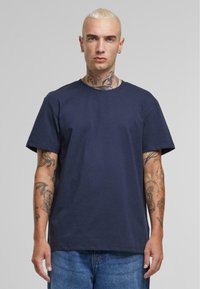 Tricou din bumbac, de culoare bleumarin, cu mâneci scurte, gât rotund și o croială lejeră, având o textură netedă și fără logo-uri sau embellishement-uri vizibile.