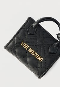 Μαύρη δερμάτινη τσάντα χειρός με υφή καπιτονέ, με χρυσό λογότυπο "LOVE MOSCHINO". Μικρή λαβή με επίπεδο σχεδιασμό και μυτερά άκρα.