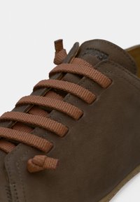 Ruskea mokkanahkakenkä pyöreällä kärjellä, jossa on tasaiset ruskeat nauhat ja yksinkertainen ommel. Sisäpuoli on beige, mikä osoittaa kestävän rakenteen.