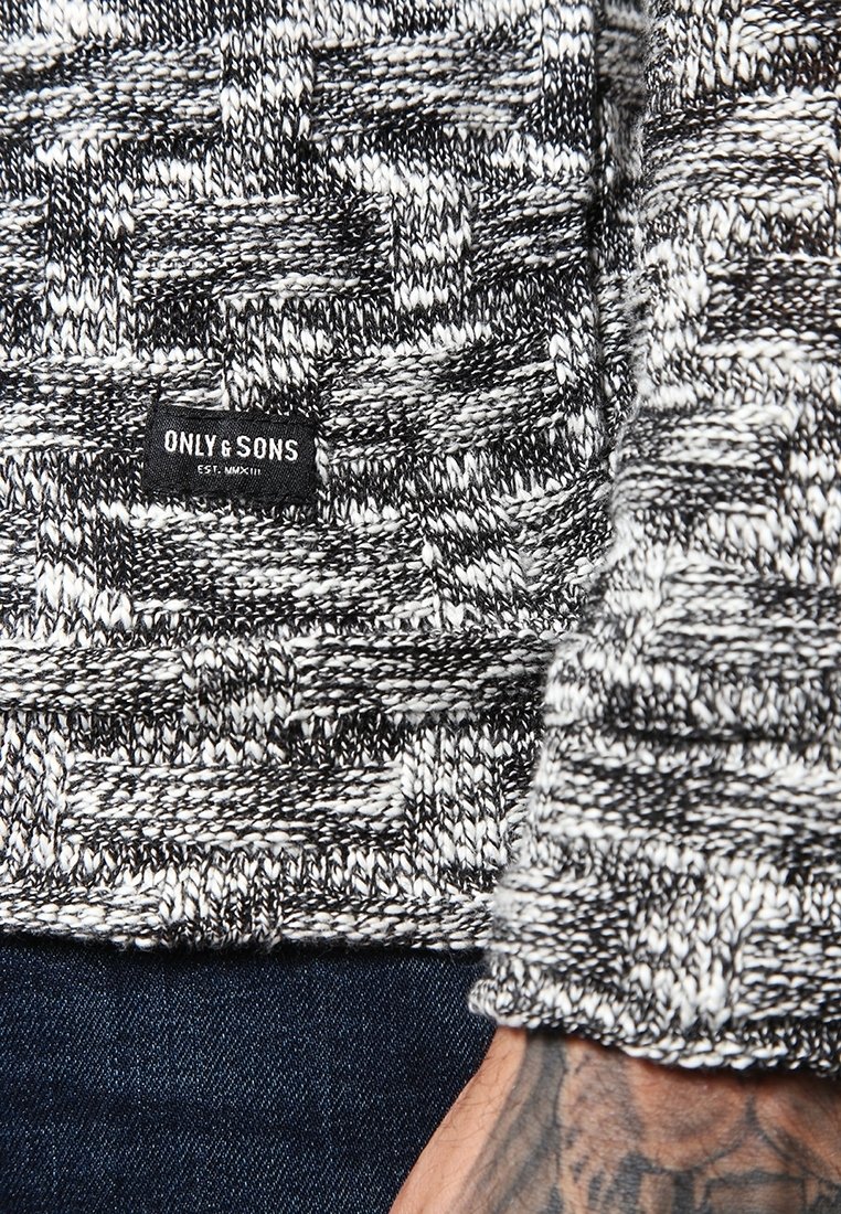 Sweter w odcieniach czerni i bieli, z teksturowanym splotem, który ma małą czarną metkę z napisem "ONLY & SONS" na dolnym brzegu.