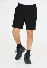 Svarta shorts med elastisk midjeband, två fickor med dragkedja och en slim passform, kombinerat med svarta vandringskängor och strumpor.