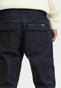 Dark blue cargo pants with a durable fabric, featuring multiple pockets, a straight cut, and subtle branding on the back pocket.