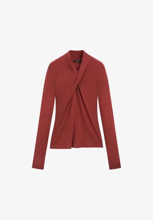Long-sleeve top in rust red, featuring a draped front design with a crossover effect, made of soft, stretch fabric. Smooth texture.
