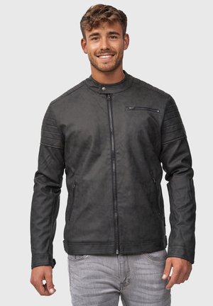 Chaqueta de cuero negra con cuello alto, cierre frontal de cremallera, bolsillos laterales y detalle acanalado en los hombros. Textura suave, diseño ajustado.