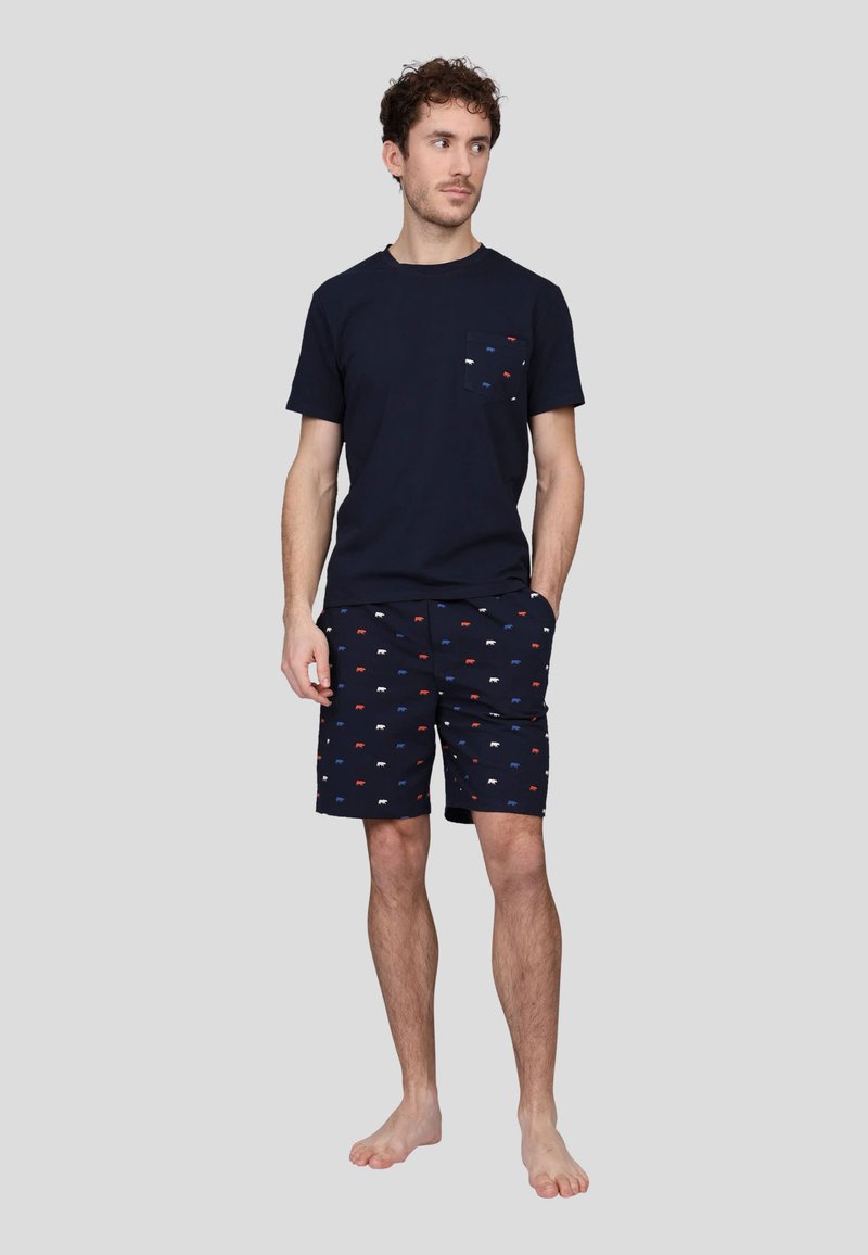 T-shirt en coton marine avec une poche poitrine et des motifs animaliers rouge, blanc et bleu. Le short assorti présente le même motif sur un fond marine uni.