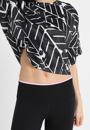Top corto negro con patrones geométricos blancos, hecho de una tela transpirable; combinado con leggins negros de cintura alta que presentan una banda de acento rosa.