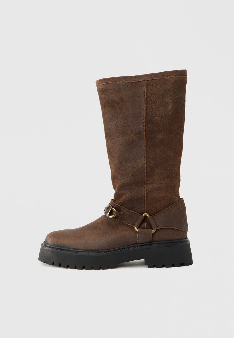 Καφέ μπότες από δέρμα σουέντ μέχρι το γόνατο με φ αρδύ μίσχο, αντιθετική μαύρη λαστιχένια σόλα και ρυθμιζόμενο λουράκι με αγκράφα κοντά στον αστράγαλο.