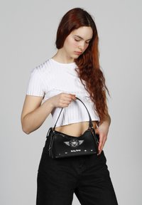 Bolso de mano negro con un diseño estructurado, que cuenta con una correa para el hombro, acentos plateados, un logo con alas y detalles de remaches.