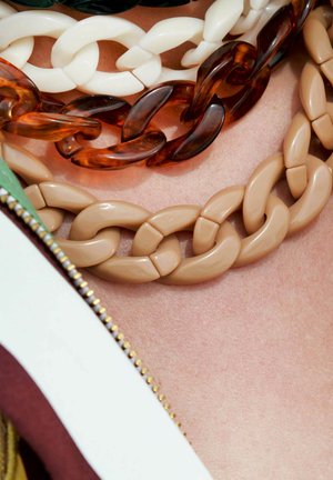 Collier chunky avec des maillons dans des teintes de beige, blanc, ambre et vert foncé. Finition lisse et brillante avec des formes de maillons variées.