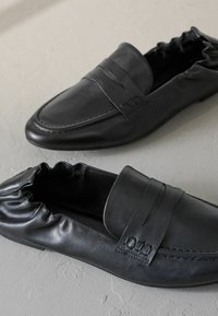 Mustadast nahast loafers ümmarguse varbaga, elastse ankle'iga, dekoratiivsete tikkimistega ja siledast viimistlusest. Tekstuuritud detailid ülaosas.