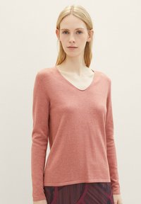 Lange mouwen V-hals top in stofroze, gemaakt van zacht, gestructureerd materiaal. Rechtdoor gesneden met een ontspannen pasvorm, gecombineerd met een patroontop.