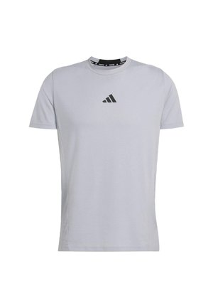 Svetlosivý krátky rukáv tričko vyrobené z mäkkej tkaniny. Má čierne logo Adidas na hrudi a zaoblený výstrih s kontrastným pásom.