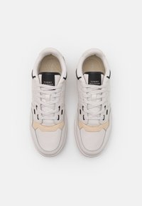 Sneakers bianchi in pelle con finitura testurizzata, caratterizzati da accenti neri e beige, design con lacci e logo sulla linguetta.