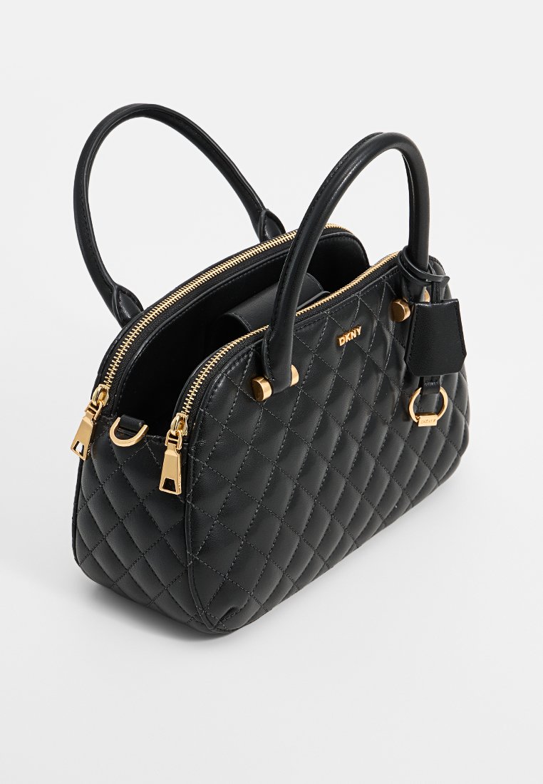 Schwarze, gesteppte Handtasche aus Leder, mit goldenen Beschlägen, zwei Griffen, zwei Reißverschlüssen und einem kleinen abnehmbaren Anhänger.