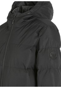 Chaqueta acolchada negra con capucha, con un acabado texturizado, cierre con cremallera y un parche con logo en la manga. Diseño ligero y aislante.