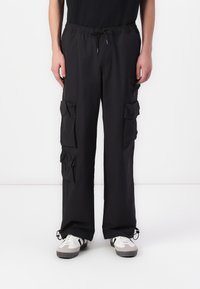 Black cargo pants with a drawstring waist, multiple patch pockets, a loose fit, and elasticized cuffs. Made from lightweight fabric.