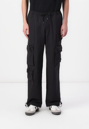 Black cargo pants with a drawstring waist, multiple patch pockets, a loose fit, and elasticized cuffs. Made from lightweight fabric.