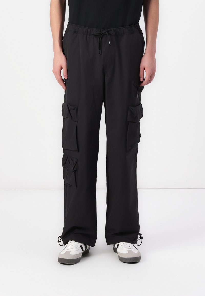 Black cargo pants with a drawstring waist, multiple patch pockets, a loose fit, and elasticized cuffs. Made from lightweight fabric.