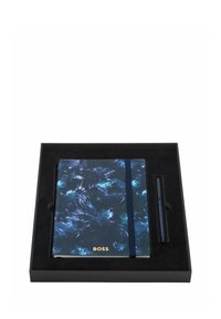 Carnet fermé bleu foncé à motifs avec élastique et inscription dorée "BOSS", accompagné d'un stylo assorti dans une boîte cadeau noire.