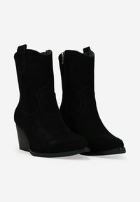 Par de botas de ante negro hasta la mitad de la pantorrilla con punta afilada, tacones en bloque apilados, cremalleras laterales y tiradores en la parte superior.