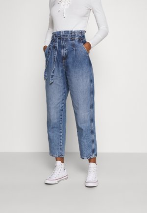 Højtaljede denimjeans med bindebånd, lyseblå vask, kort ben og sidelommer, kombineret med hvide højtop-sneakers.