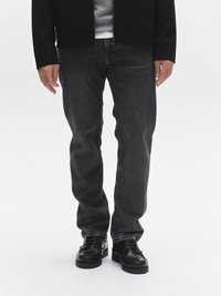 Tamsiai pilkos spalvos džinsai tiesaus kirpimo, derinami su juodais odiniais batais ir juoda užtrauktuku užsegama striuke ant pilkos spalvos džemperio.