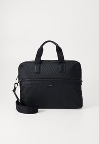 Sac à dos en nylon noir pour ordinateur portable avec deux poignées, une sangle détachable, une poche zippée et un branding subtil. Surface texturée avec un design élégant.