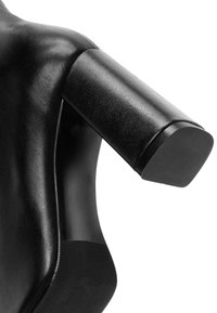 Silla ergonómica negra con respaldo que presenta un soporte para los hombros redondeado y acolchado, textura de cuero suave y un acento geométrico en la base.