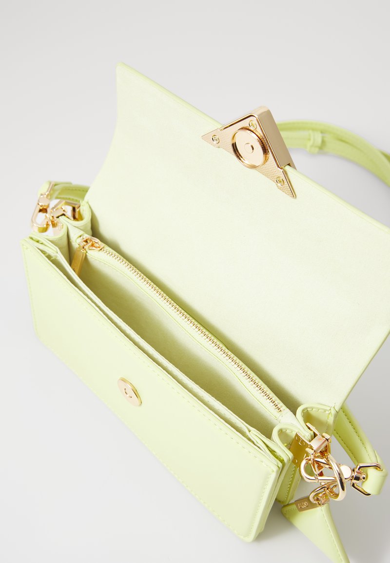 Sac à main en cuir vert clair avec un fermoir triangulaire en ton doré, une poche zippée intérieure et plusieurs compartiments pour l'organisation.