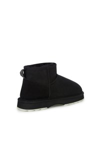 Czarne zamszowe botki za kostkę z miękką wyściółką wewnętrzną, niskim profilem i teksturowaną gumową podeszwą. Posiadają pętelkę z tyłu ułatwiającą zakładanie.