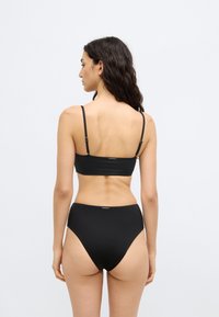 Μαύρο σετ μαγιό δύο τεμαχίων με cropped τοπ σε λεπτές τιράντες και ψηλόμεσο κάτω μέρος, με λεία υφή και μινιμαλιστικό σχέδιο.