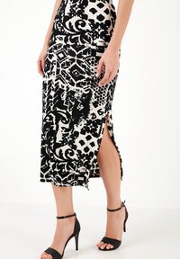 Gonna midi a fantasia in bianco e nero con spacchi laterali, realizzata in tessuto testurizzato. Presenta un design aderente che mette in risalto la forma del corpo.