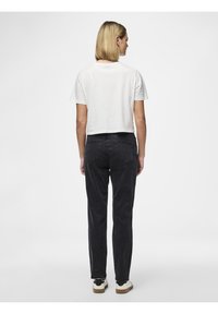 Hvit, kort t-skjorte, svarte jeans og kremfargede sneakers. Enkelt design med korte ermer; jeansene har en tettsittende silhuett og lommer.
