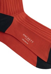 Calze rigate rosse con punta e tallone neri. Presentano il marchio "Hackett London" e la scritta "Hand Linked Toe" in bianco. Texture liscia.