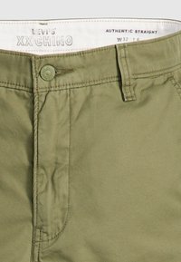 Pantalon chino XX vert olive de Levi's avec fermeture à bouton, passants de ceinture et ceinture intérieure blanche étiquetée "Authentic Straight W32 L6".