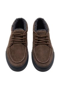 Zapatos de ante marrón con forro de piel de oveja gris, punta redonda y suela de goma negra. Presentan cordones con un diseño clásico de ojales.