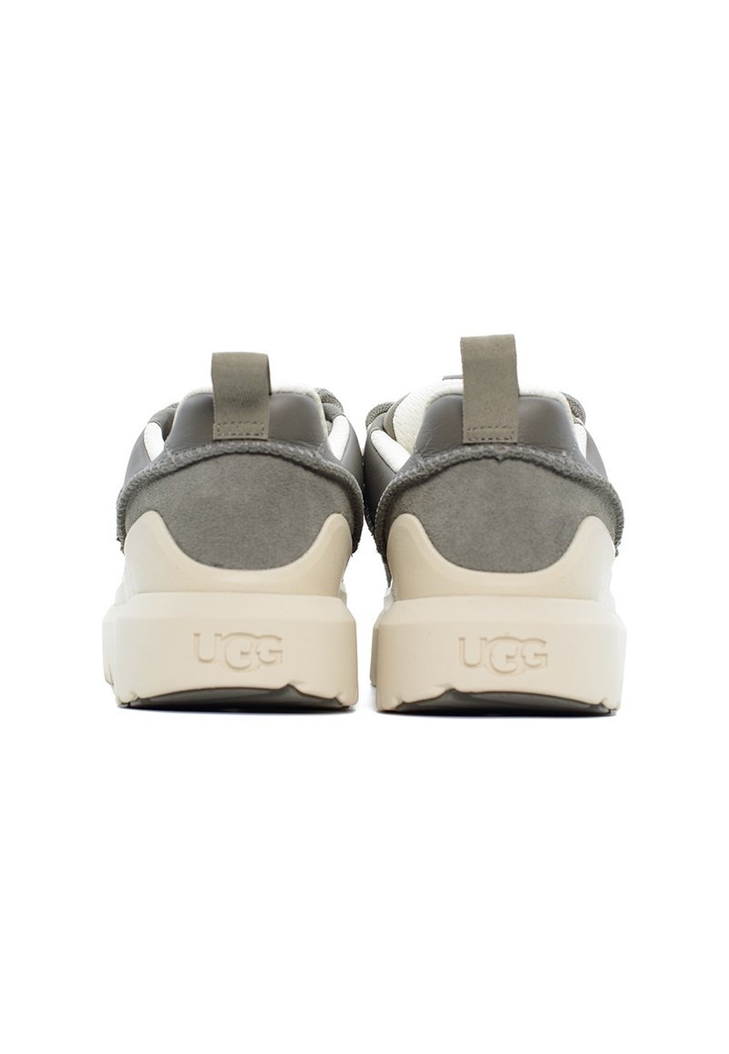 Grijze en beige sport schoenen met een gladde suede bovenkant, foam zool en een minimalistisch ontwerp. Voorzien van een aantrek lipje op de hiel.