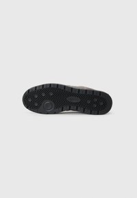 Sole in gomma nera con profonde scanalature per una migliore aderenza, con accenti circolari e una superficie texture per grip e durata.
