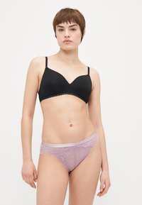 Schwarzer gepolsterter Bralette mit gewelltem Spitzenrand; kombiniert mit lilafarbenen Spitzenpantys mit Blumenmustern und einem glatten Bund.